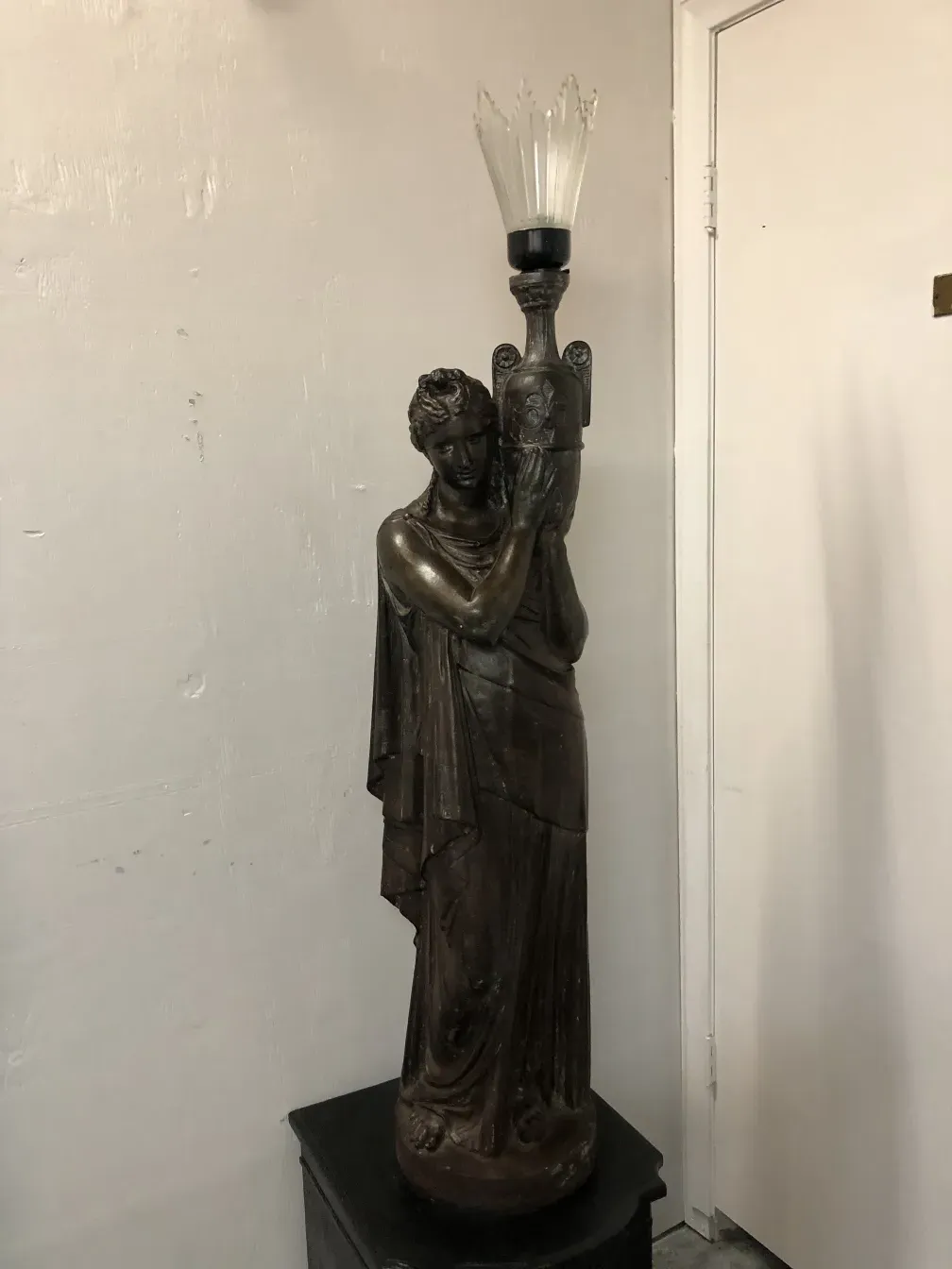 Antique floor lamp with figure holding the design, cozy atmosphere.