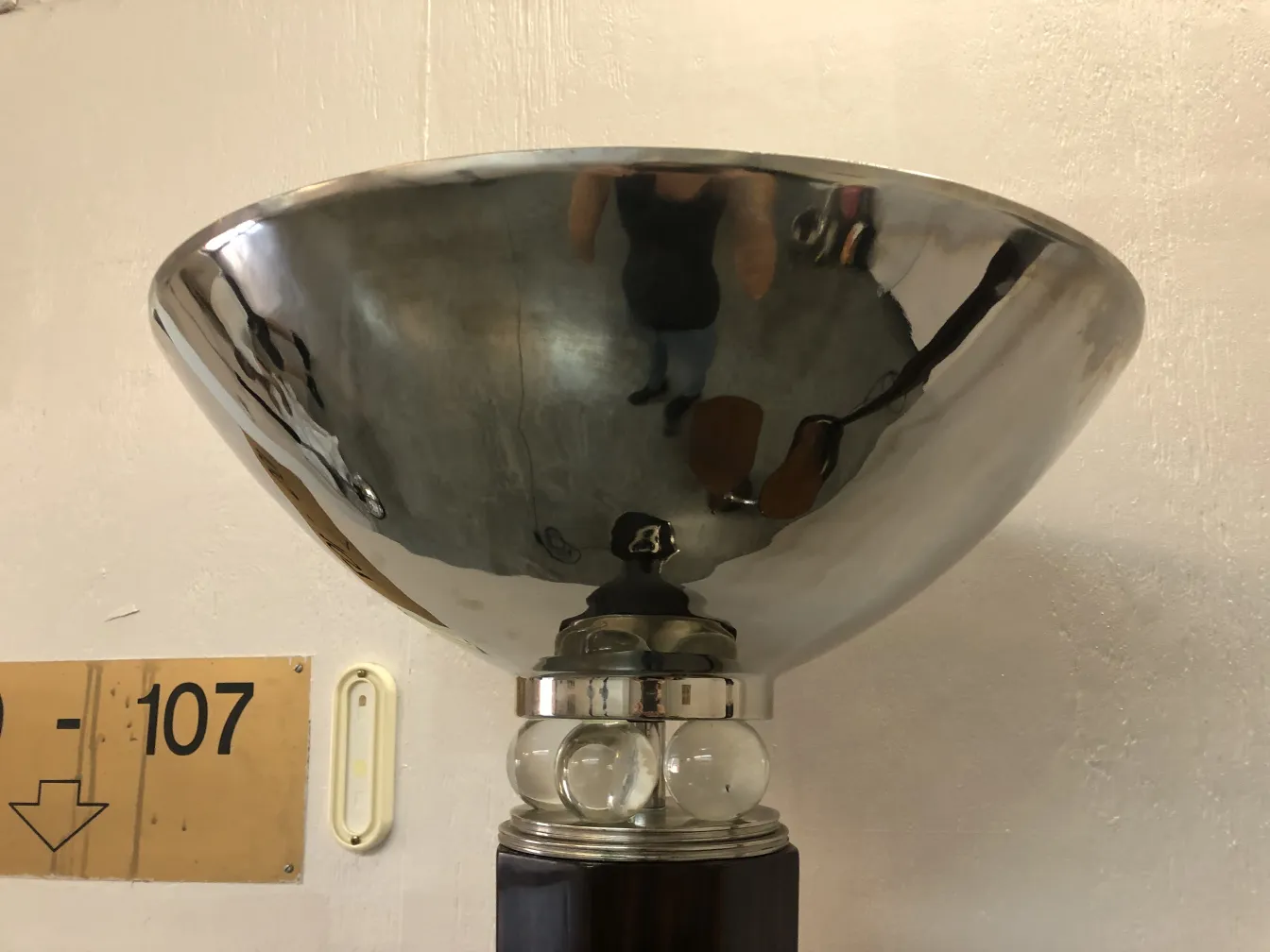 Antique floor lamp with shiny bowl in a simple setting.