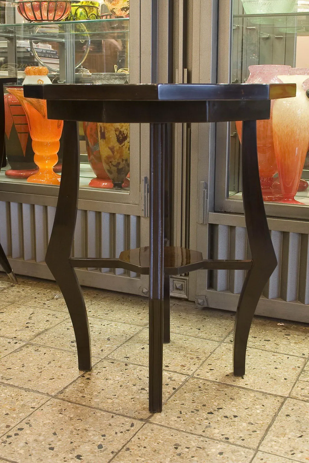 Antique small table with elegant design, near colorful vases.