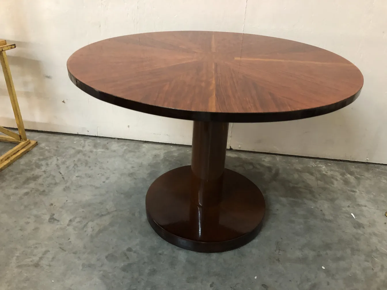 small antique round table with a sturdy base in a simple setting.