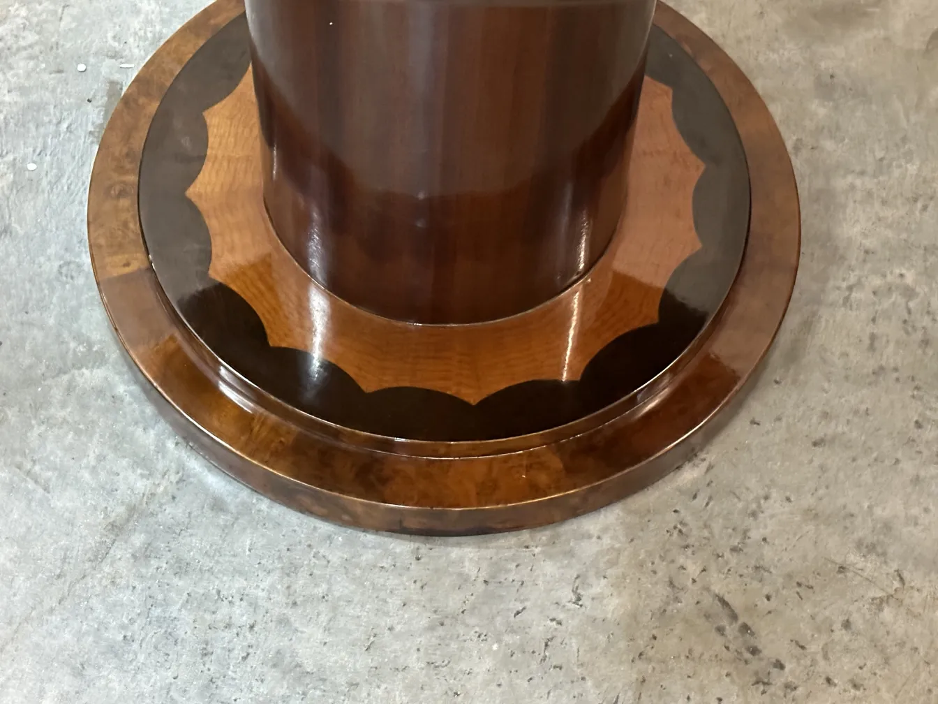 Antique round base with curved details, simple surroundings.