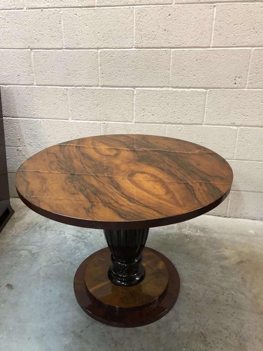 Two small antique tables in a modern setting with a brick wall