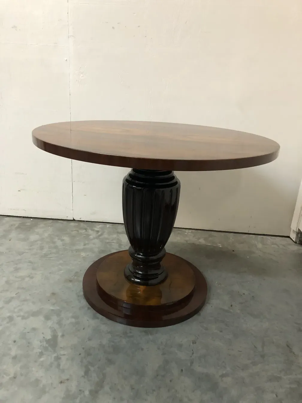 2 antique small tables with circular base and flat top, in a simple setting.