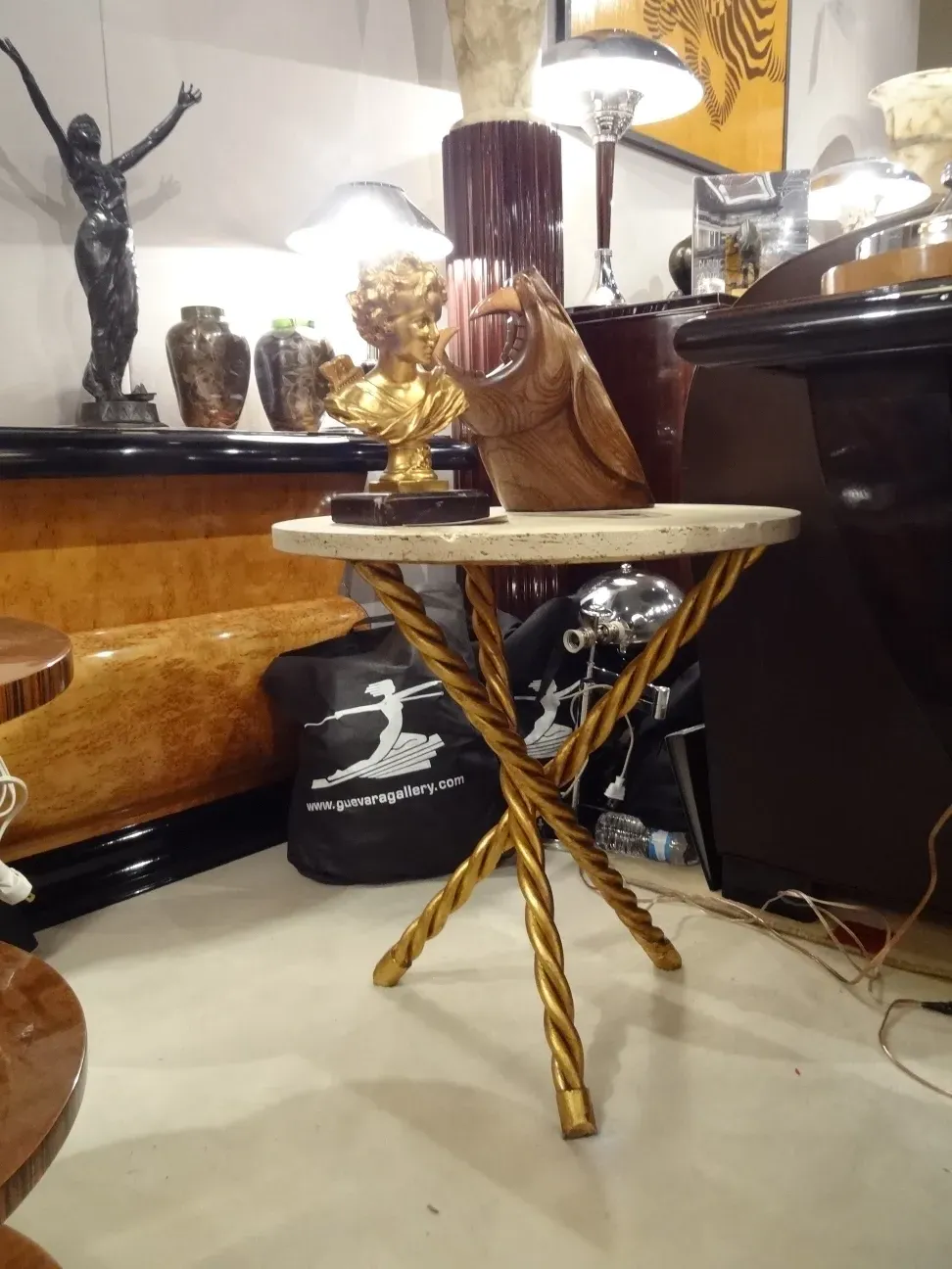 Two antique small tables, one with golden decoration and another with an elegant base, in an antique setting
