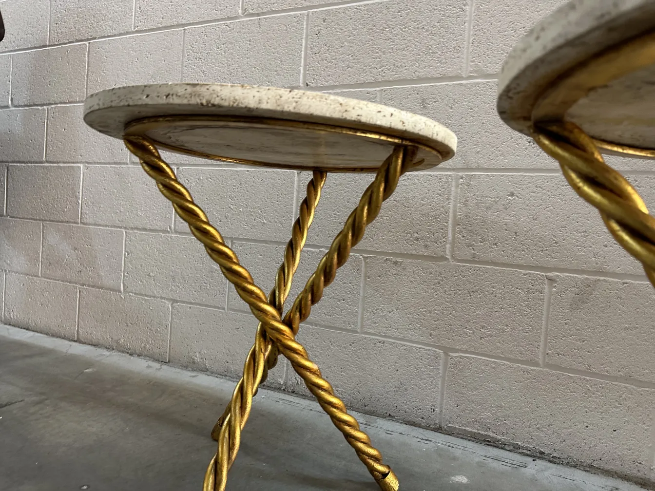 Two antique small tables with a gold base and a light top in a modern setting