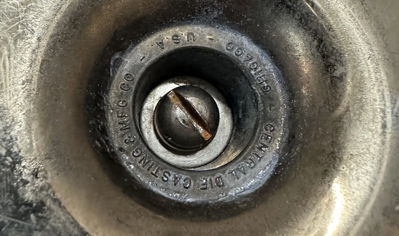 Antique round ashtray with textured surface, visible screw detail in the center.