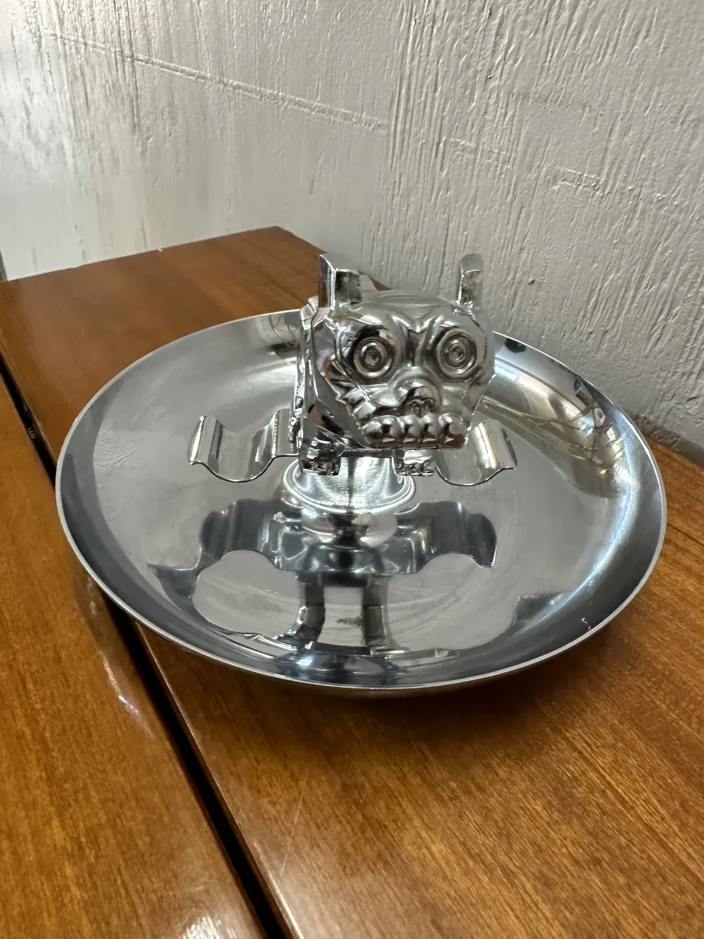 Antique ashtray with shiny animal figure, on wooden surface