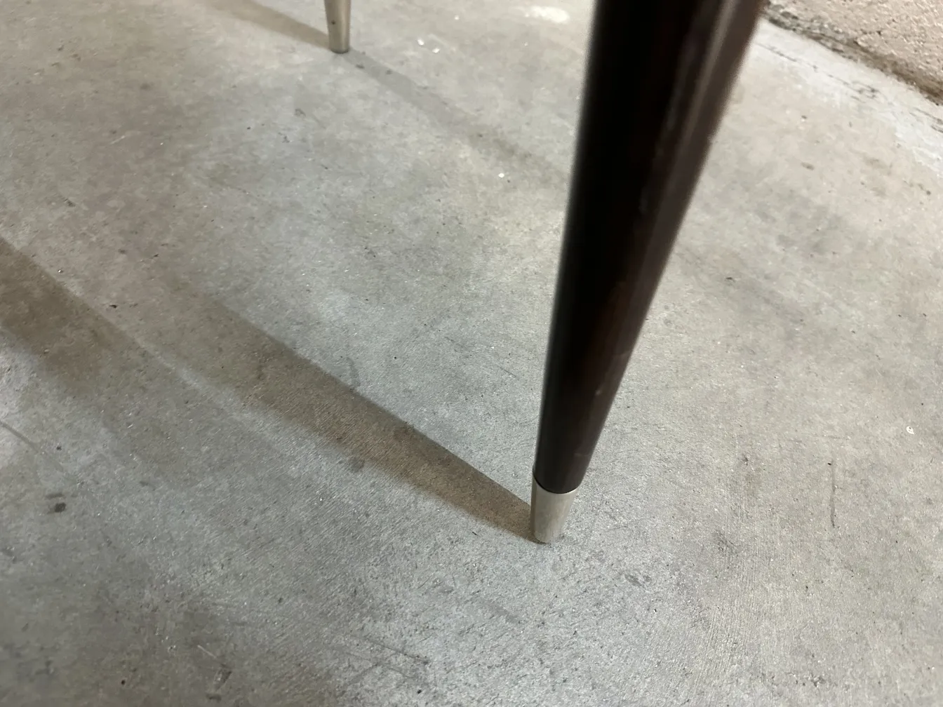 Detailed view of legs of 12 antique chairs carlo mollino, with shadows on the floor.