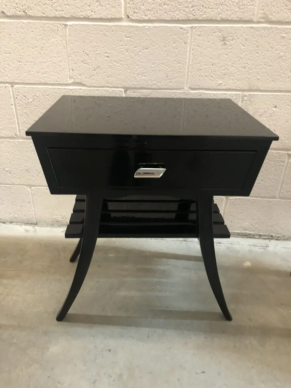 Antique bedside table with drawer and curved legs in a minimal setting.