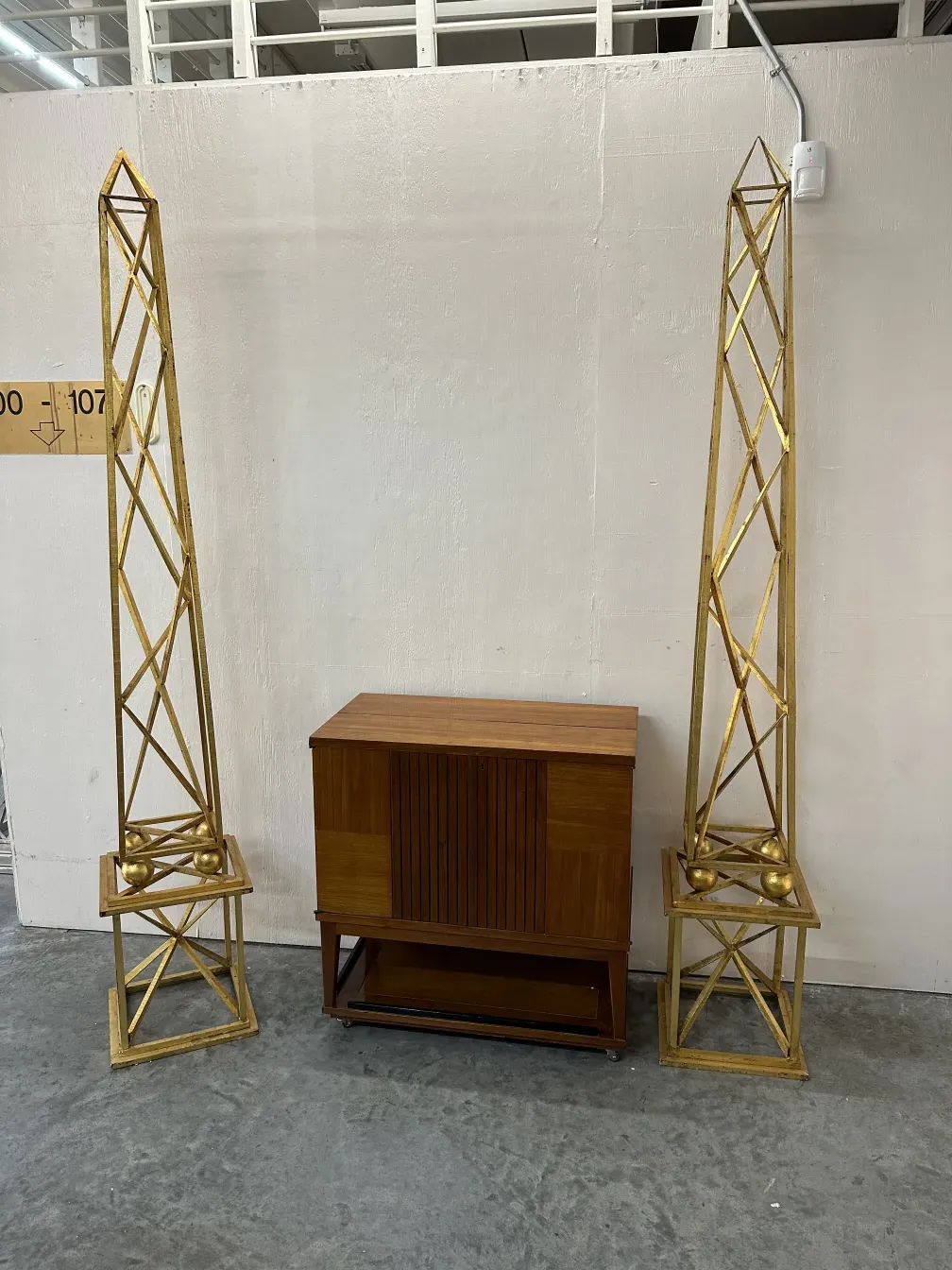 two antique gold obelisks in a decorative setting