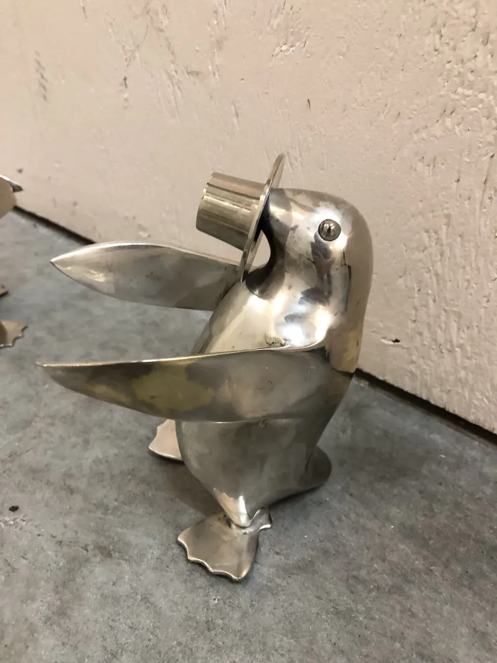 Antique metal decorative penguins, one wearing a hat, on gray background