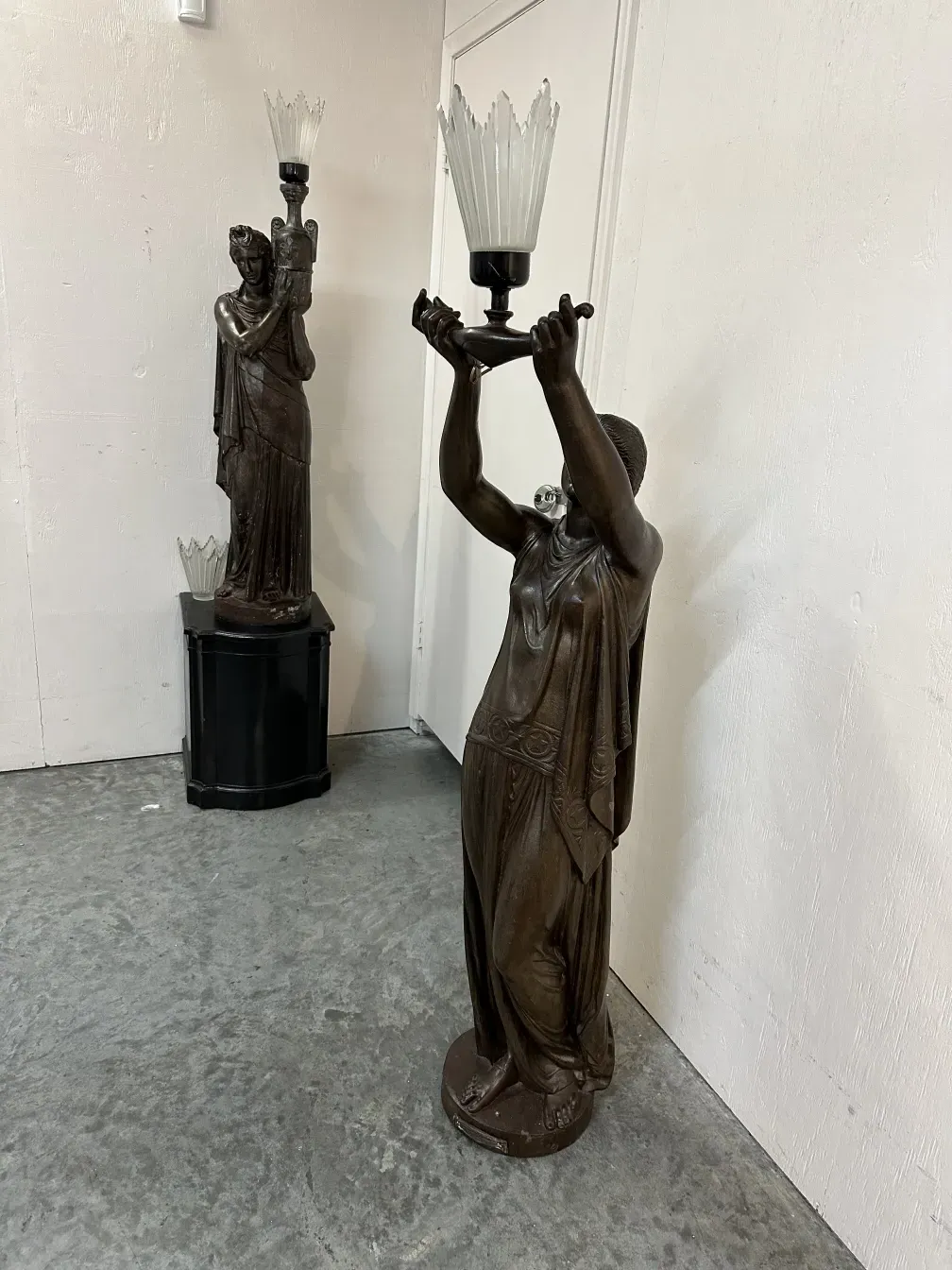 antique sculpture featuring a human figure holding a lamp