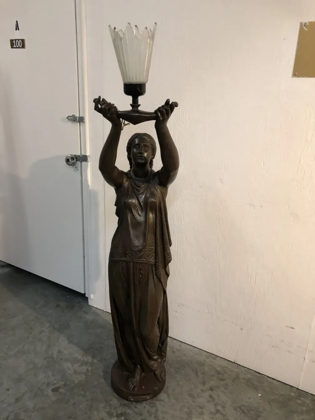 Antique sculpture Val D´Osne depicting figure holding light in a simple setting