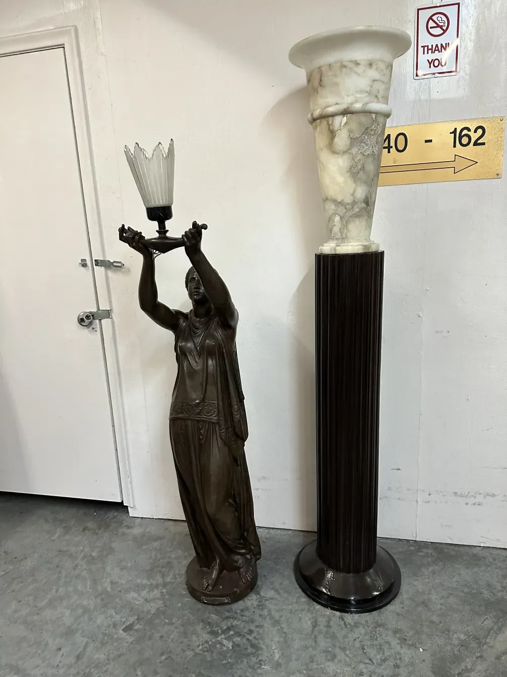 antique sculpture of a female figure holding a crystal lamp, light background.