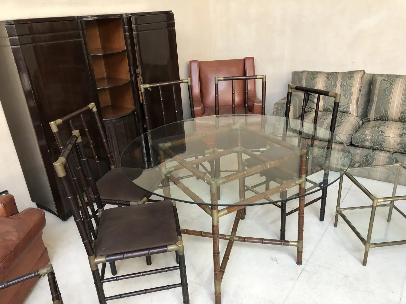 Antique dining table by William Billy Haines for 6 people, surrounded by chairs and a dark cabinet.