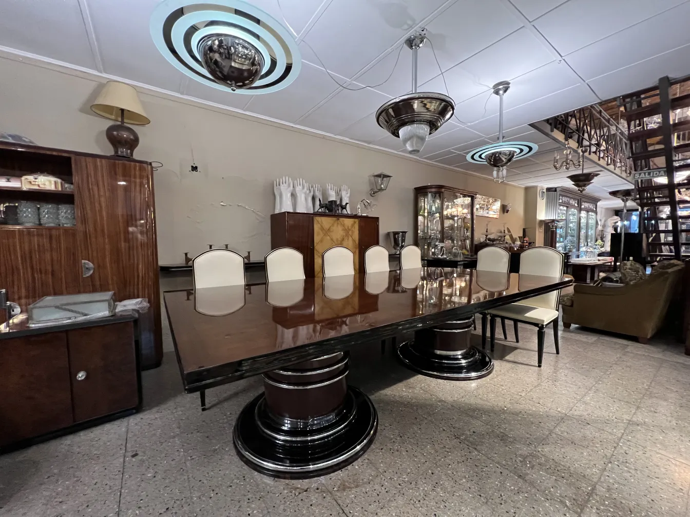 Antique dining table for 14 people with white chairs in an elegant setting.