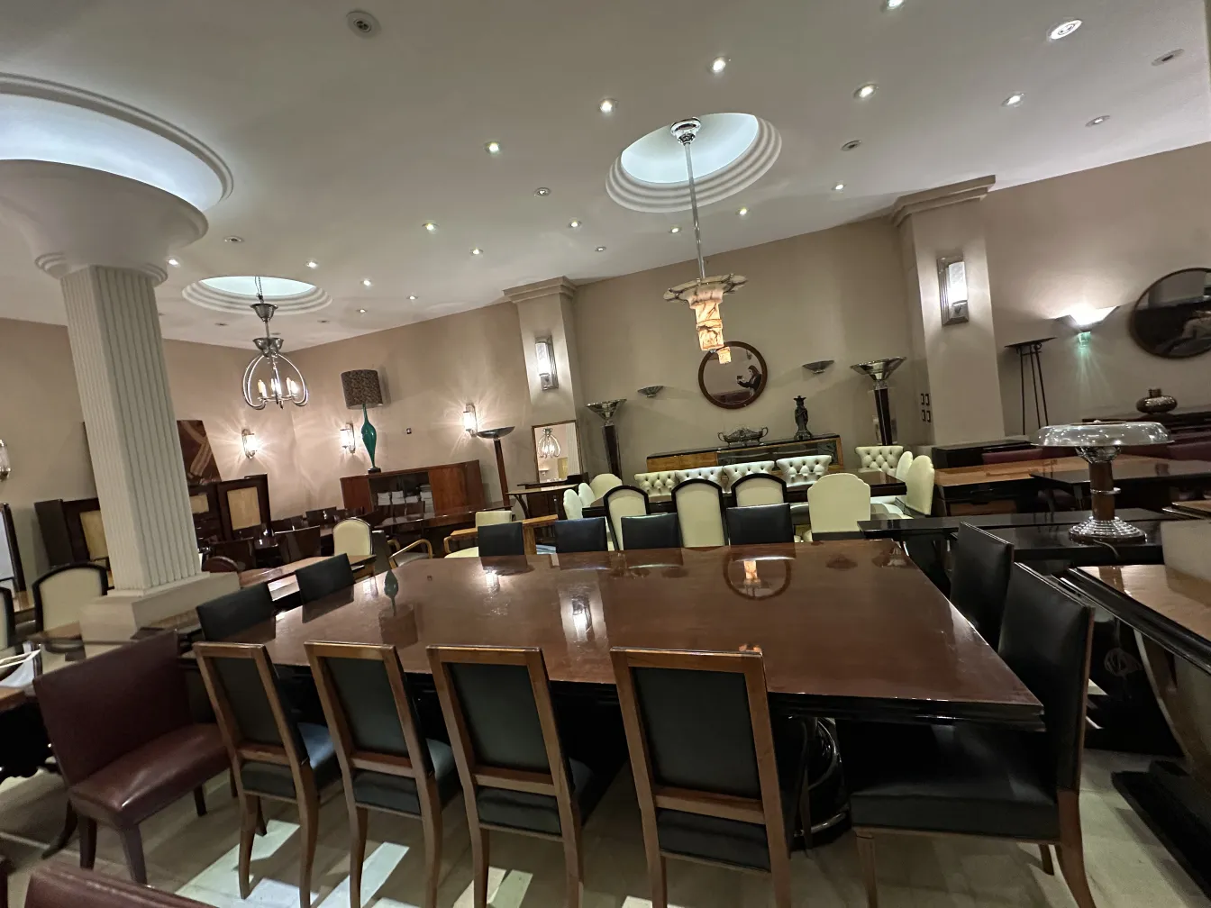 Antique dining table for 14 people with black chairs in an elegant setting.