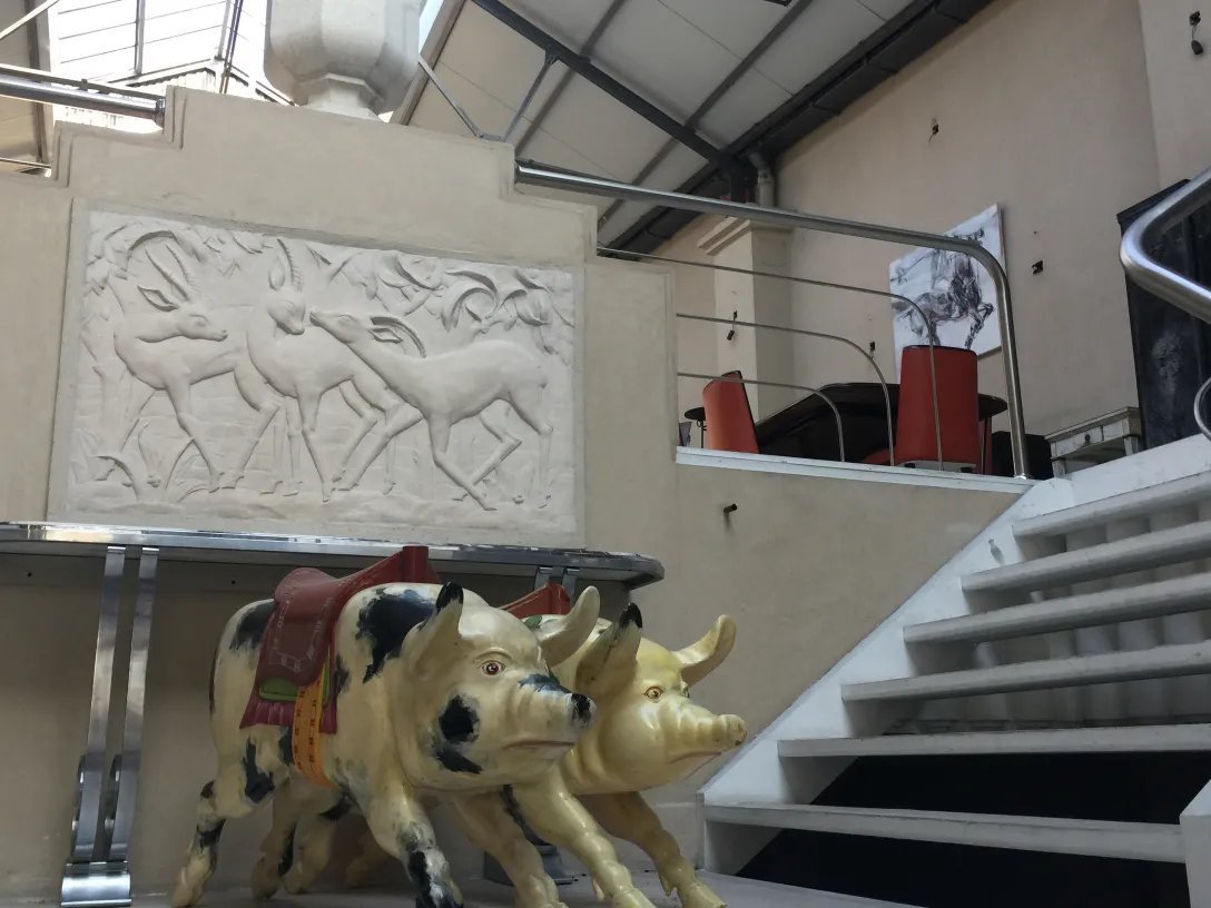 Antique sculpture of a pig in a decorative setting.