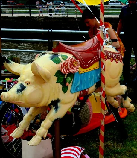 Antique decorative sculpture of a pig with flowers, colorful and vibrant.