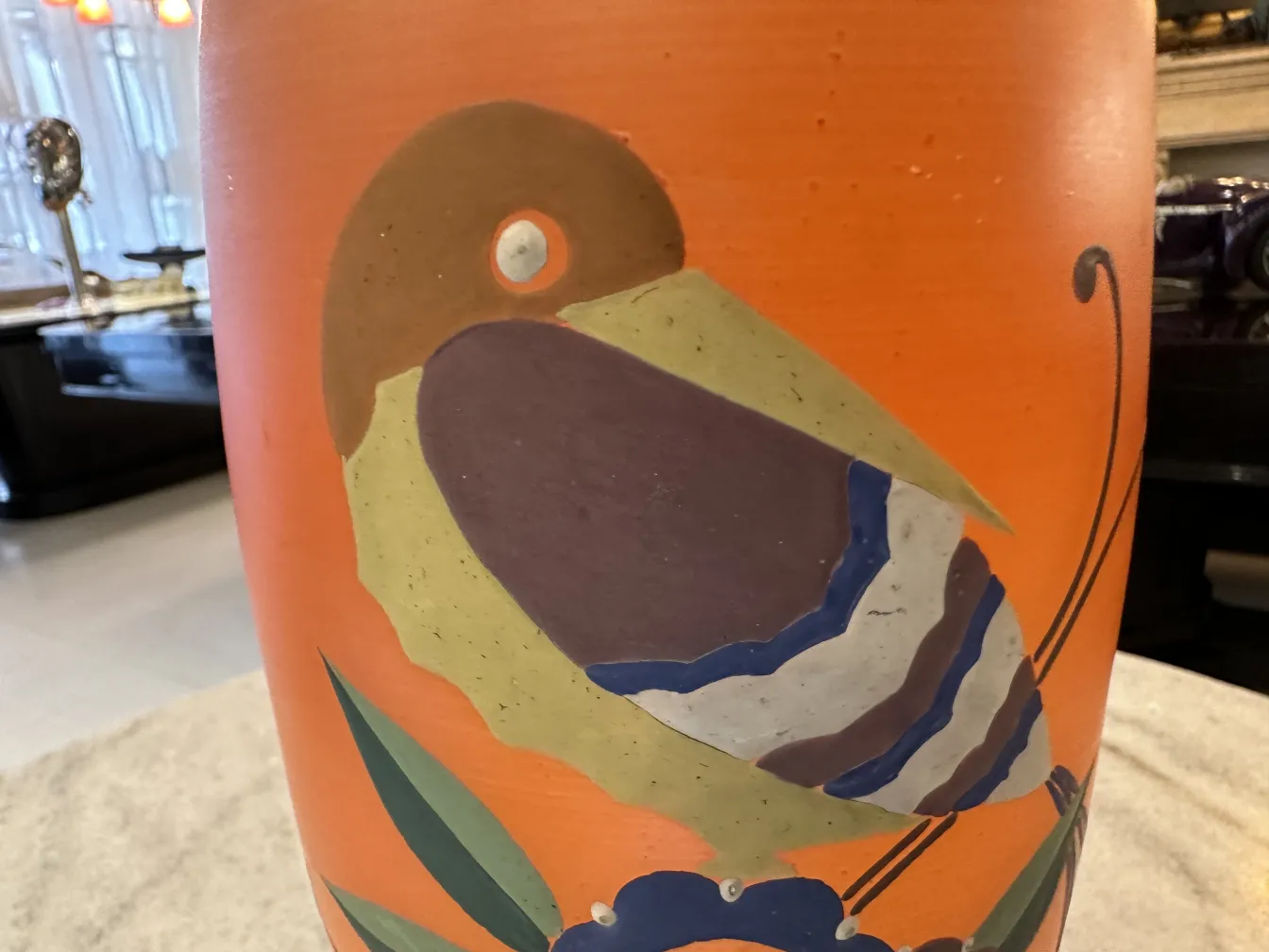 vase antico con design di uccelli colorati su sfondo arancione