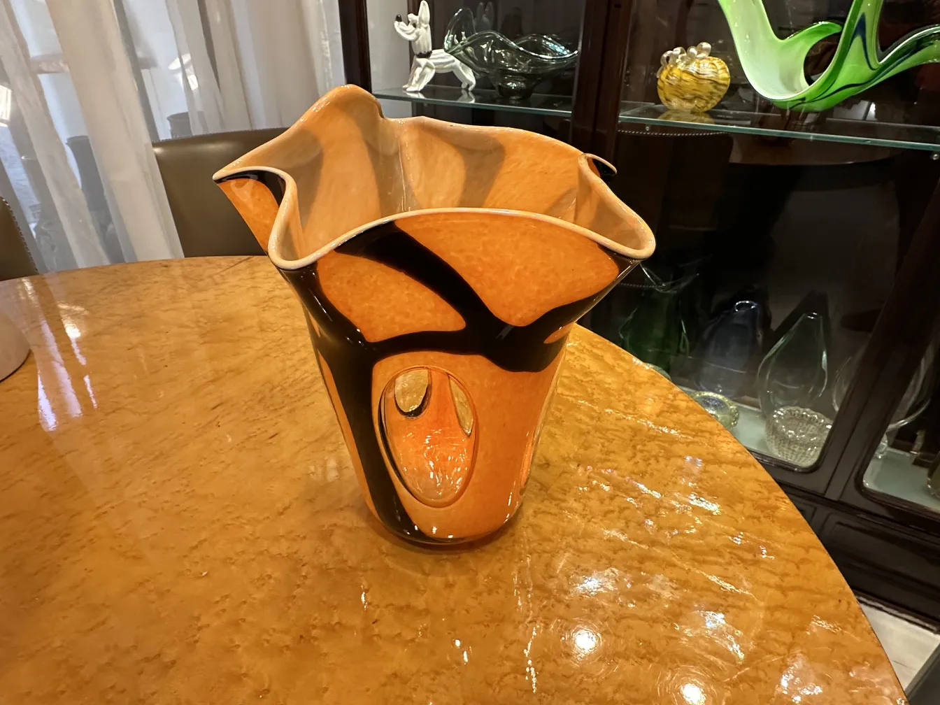vase antico con base larga e curve eleganti, di colore arancione e nero, su tavolo di legno
