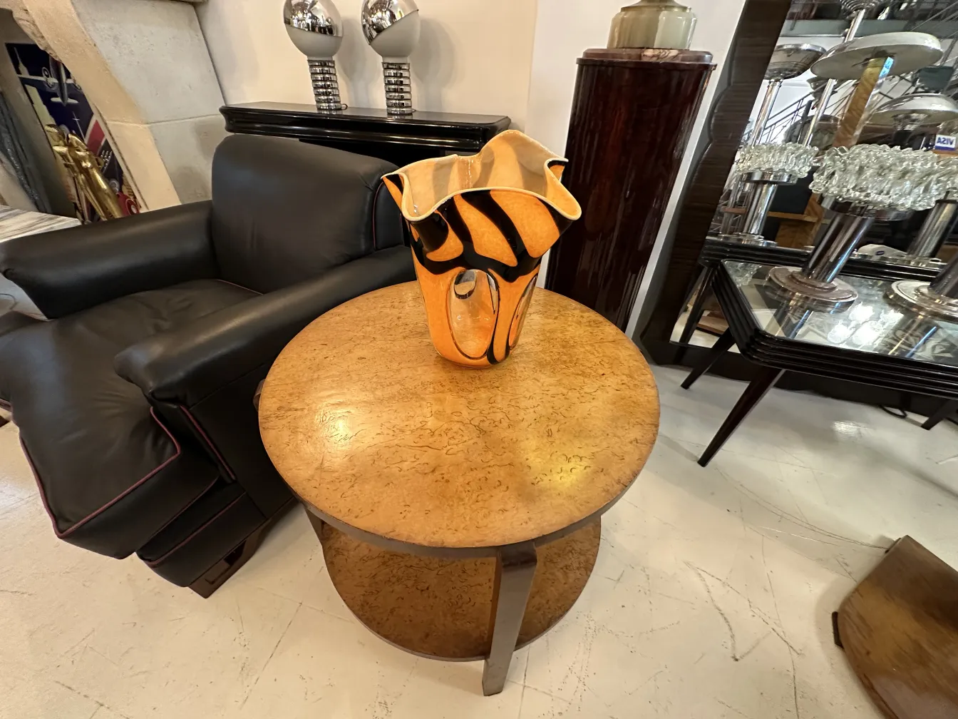 vaso antico arancione con design nero, su tavolo di legno, divano nero sullo sfondo