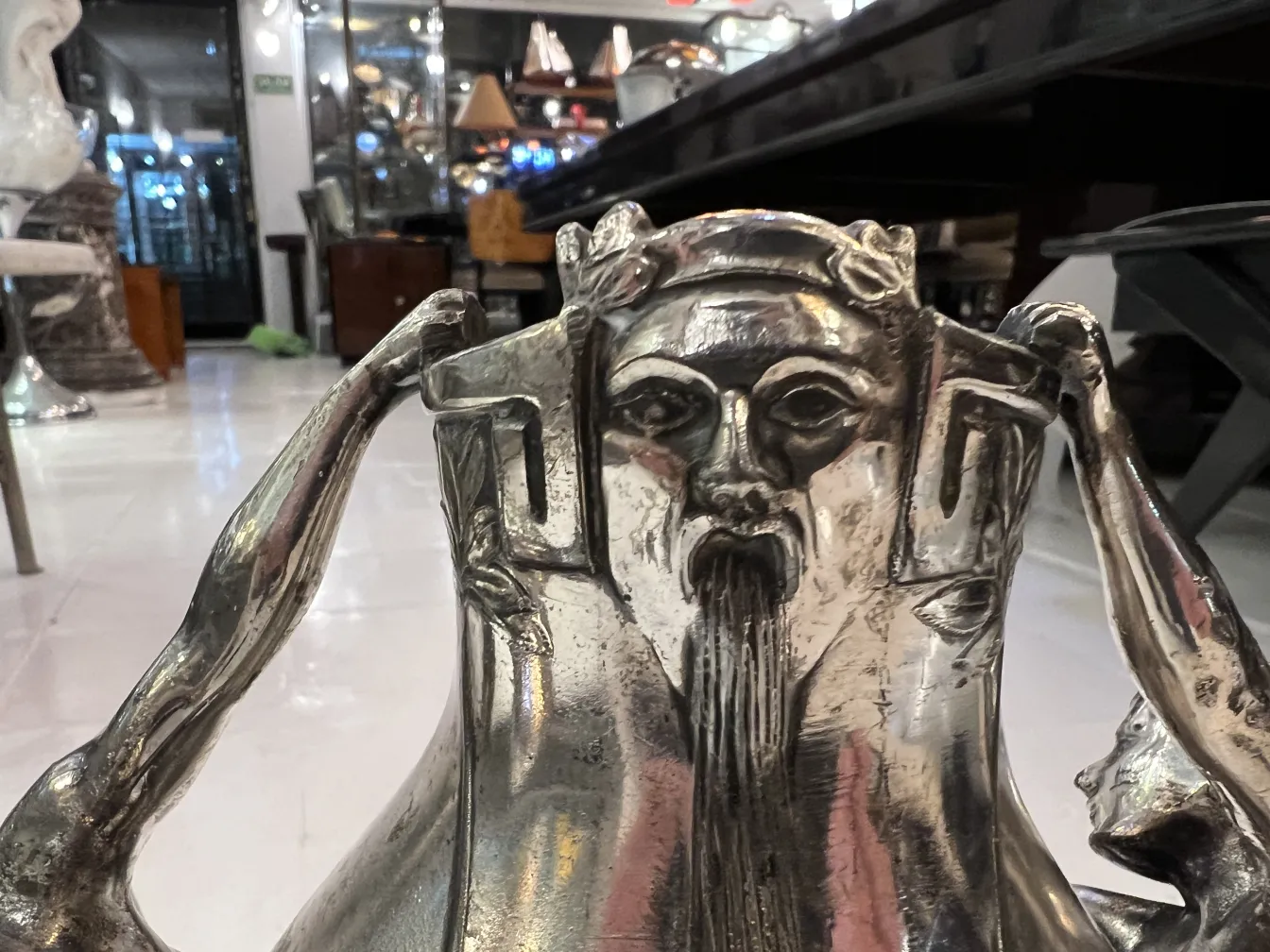 Vaso antico con design scultoreo sopra e sfondo elegante. Mostra un'atmosfera d'antiquariato.