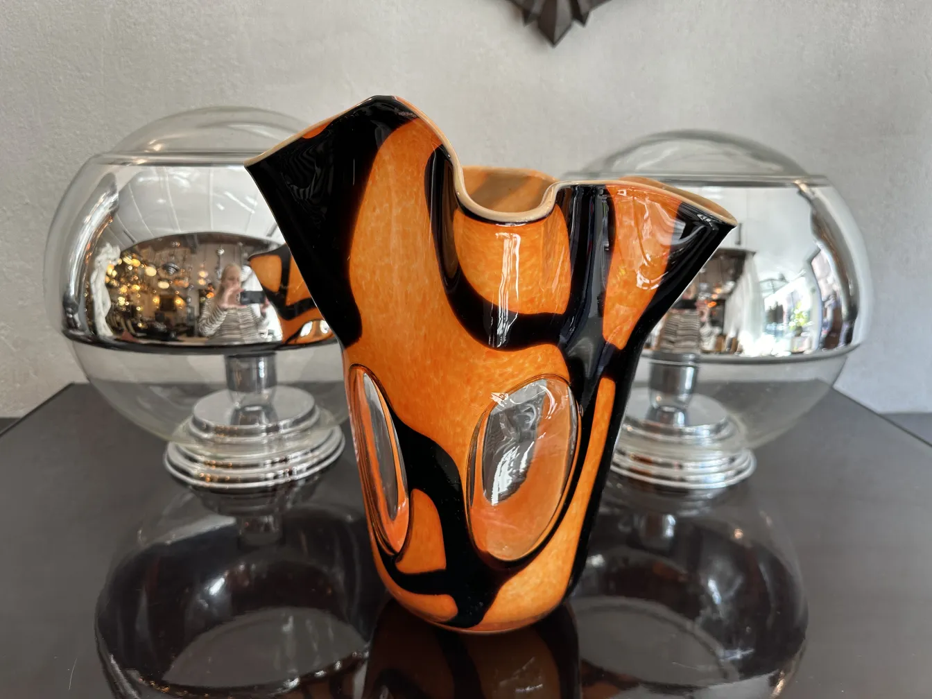 vaso antico arancione e nero con forma distintiva, circondato da elementi decorativi moderni