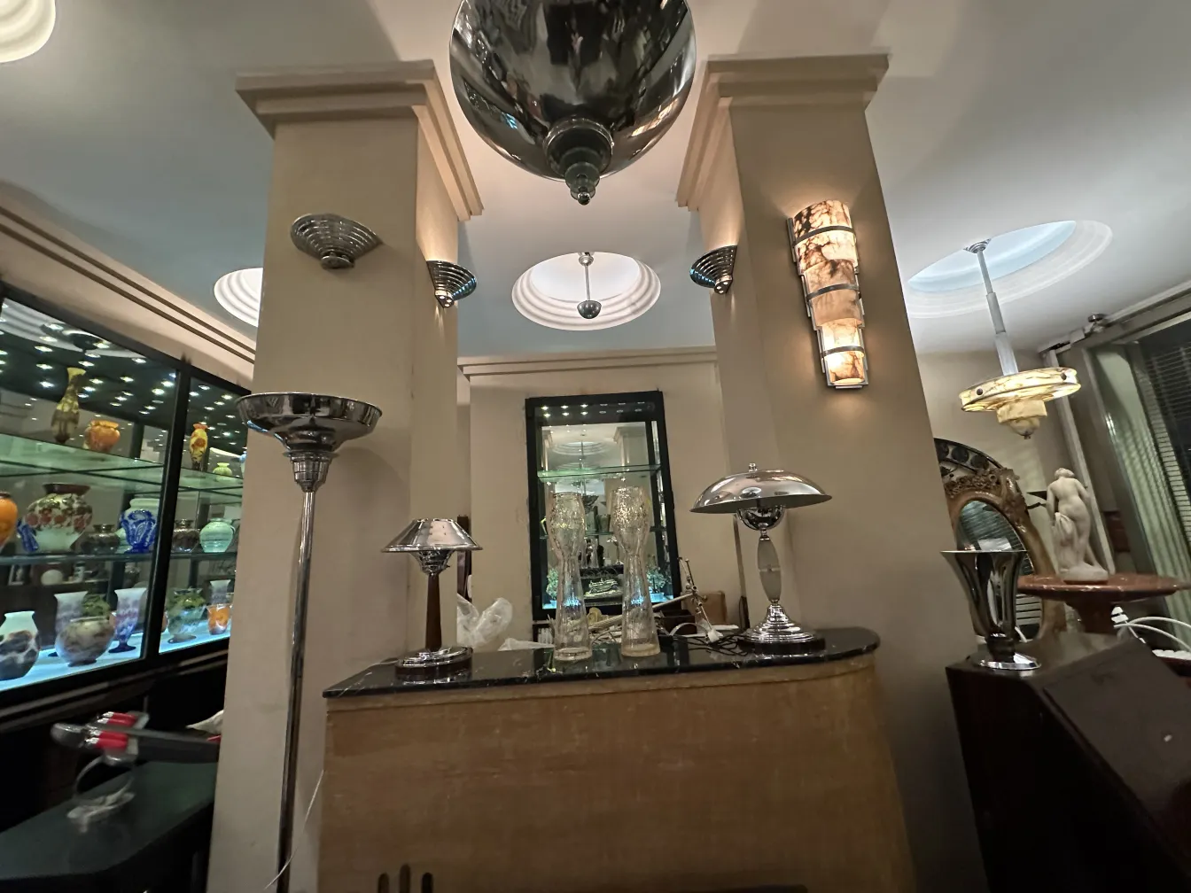 Due vasi antichi su un supporto, circondati da luci e oggetti decorativi in un ambiente elegante.