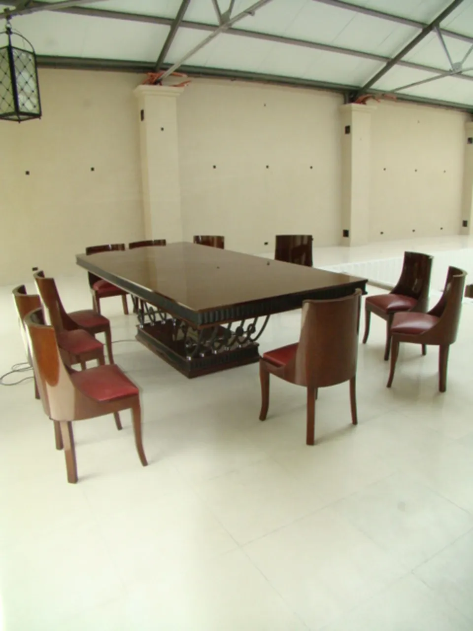 Antique dining table in Art Deco style for 12 people, surrounded by chairs in a spacious environment.