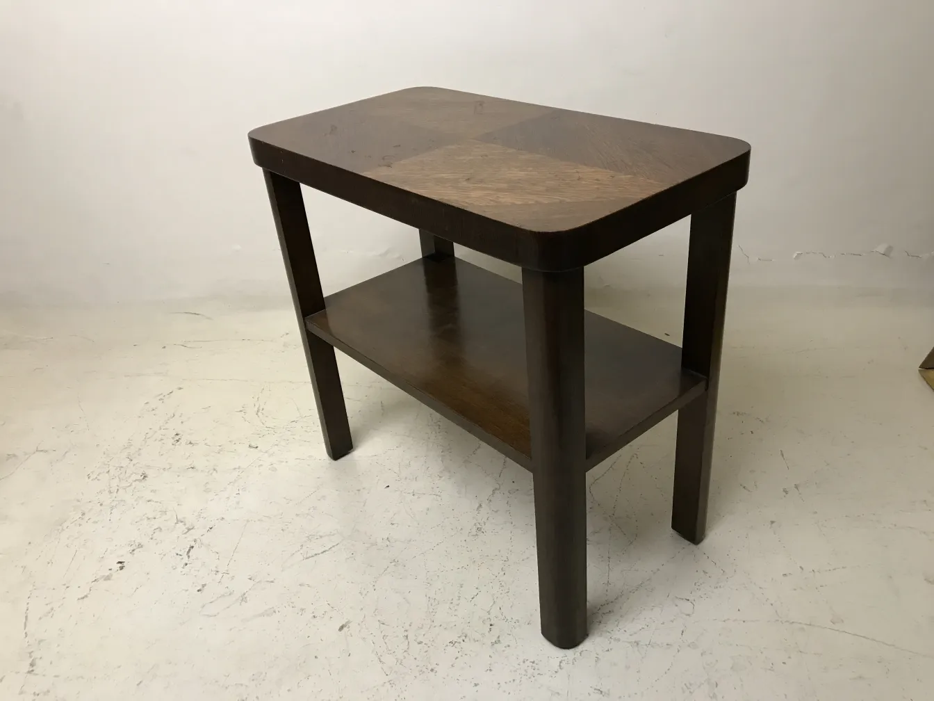 antique table with a lower shelf in a neutral setting
