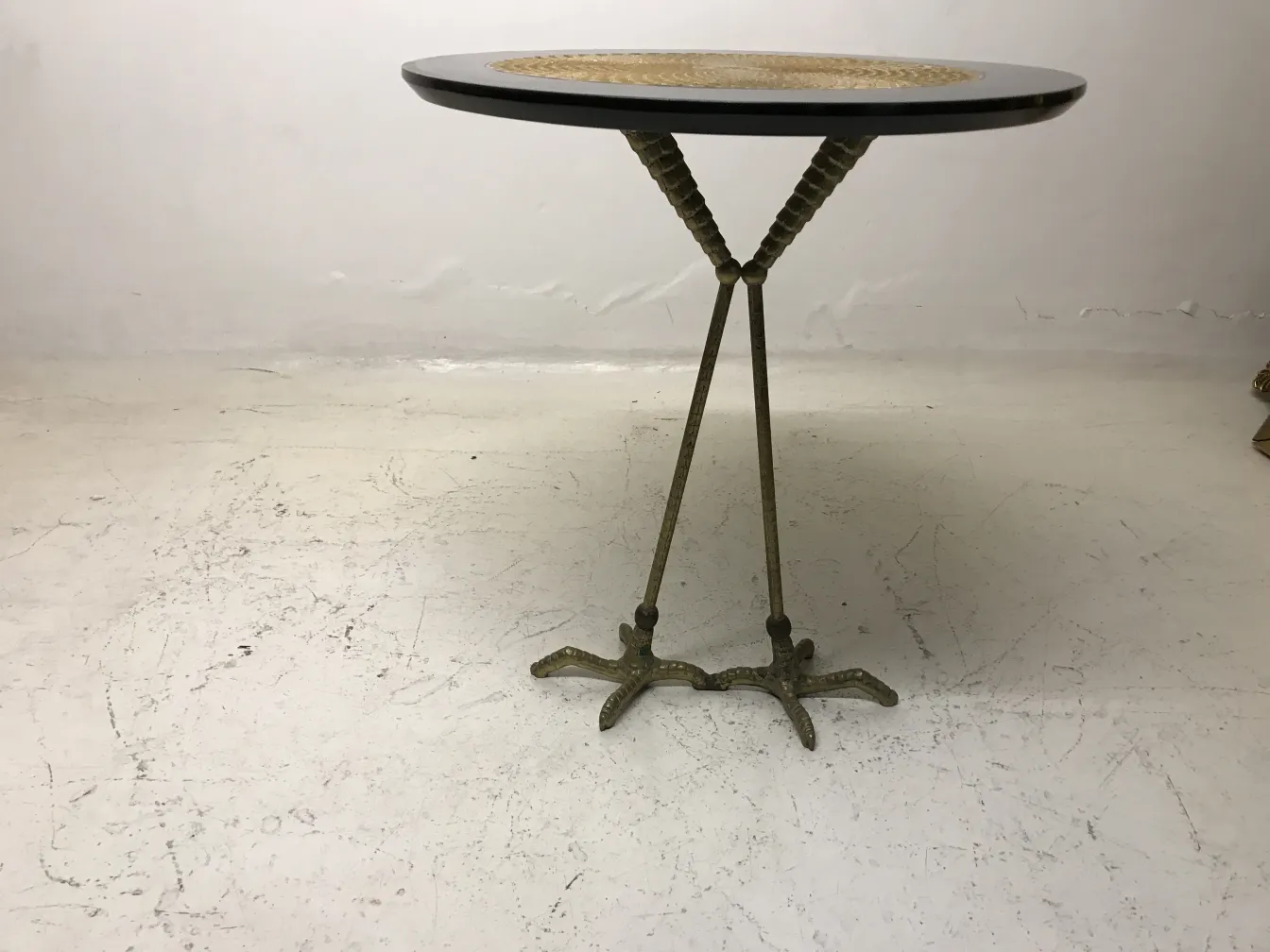 Side view of two antique small tables with decorative base in the background