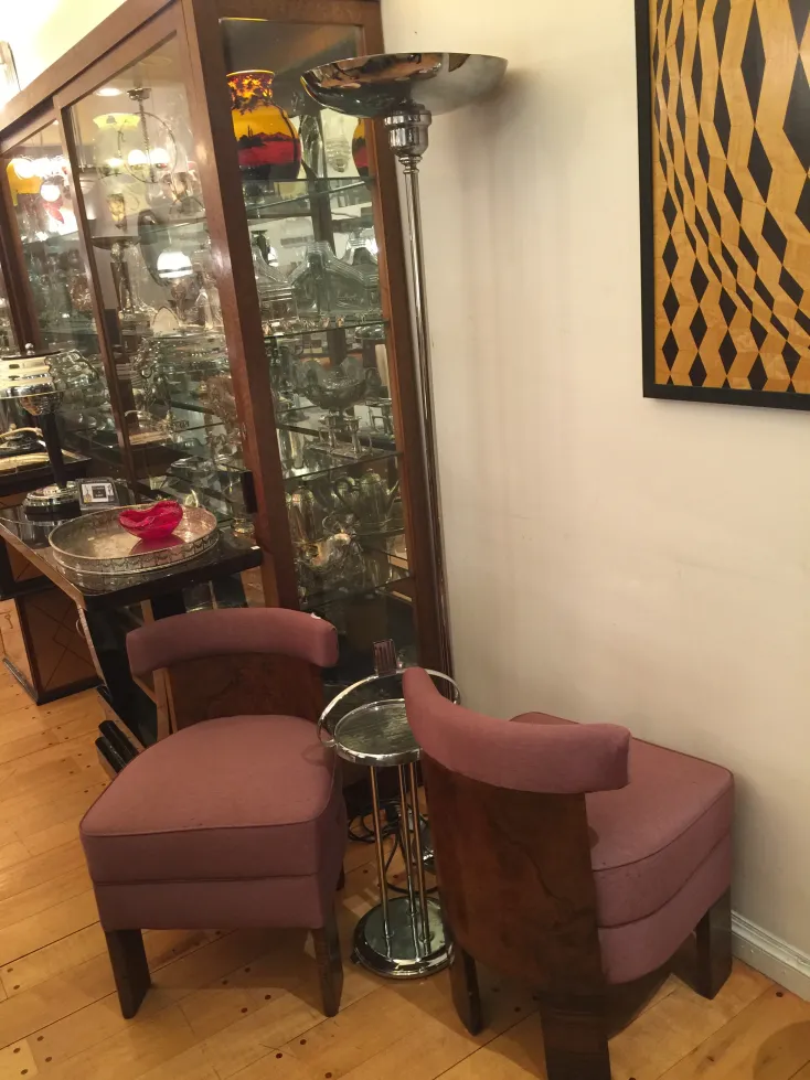 Two antique armchairs to be restored in a refined setting with a modern lamp in the background.