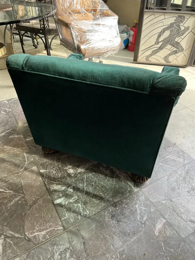 Two antique dark green armchairs in a restoration environment, with a decorative background.