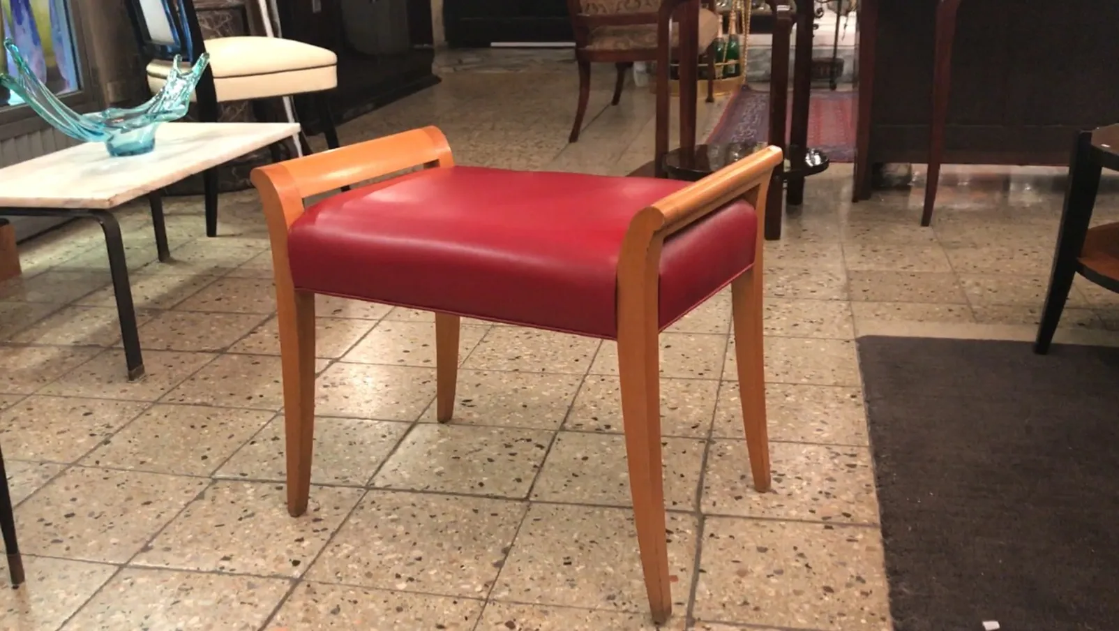 sgabello antico rosso con gambe chiare in un ambiente elegante