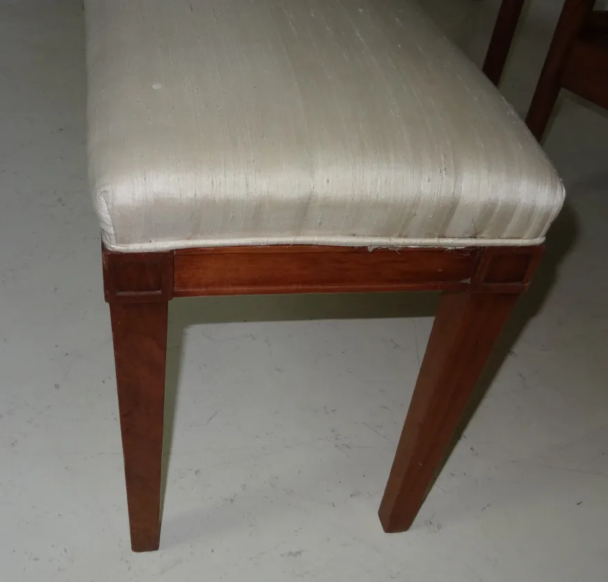 dettaglio di uno sgabello antico con seduta chiara e gambe dritte, atmosfera classica