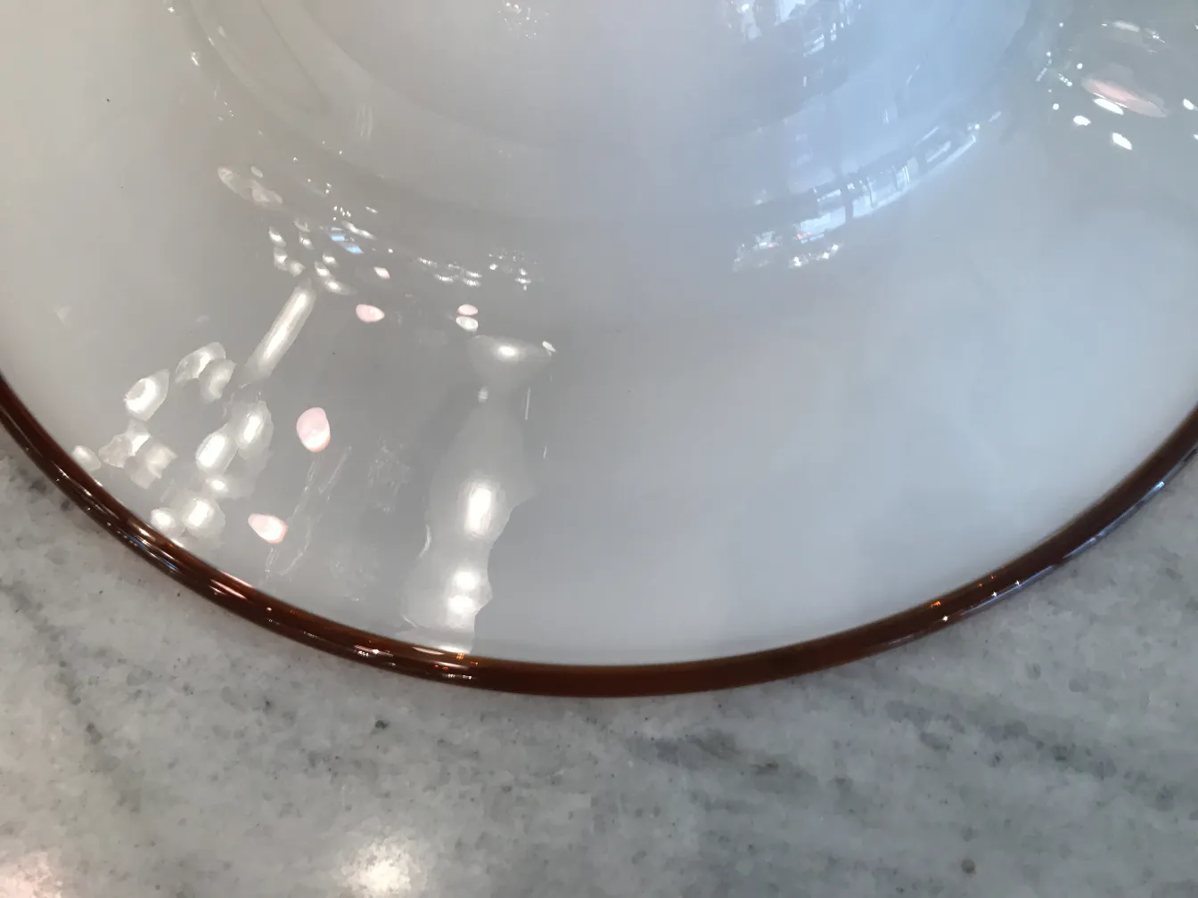 Antique white hanging lamp with brown edges illuminating the space.