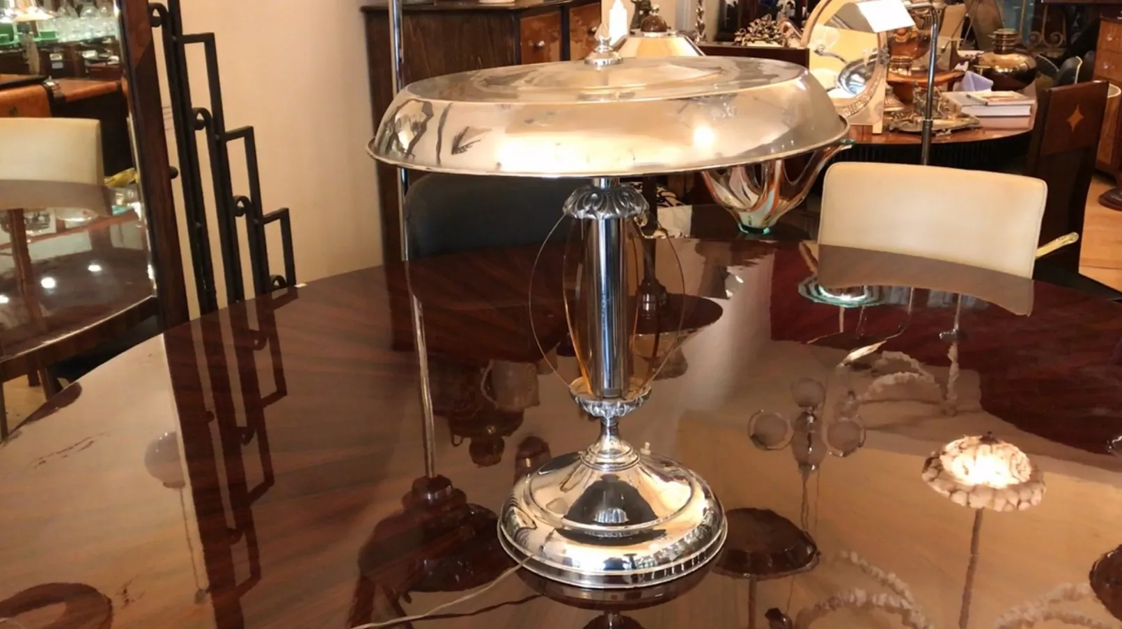 Luminária de mesa antiga em estilo Art Deco sobre uma mesa brilhante, cercada por móveis vintage.