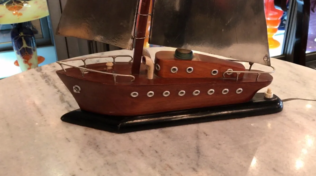 Luminária de mesa antiga em forma de barco, iluminando um espaço acolhedor.