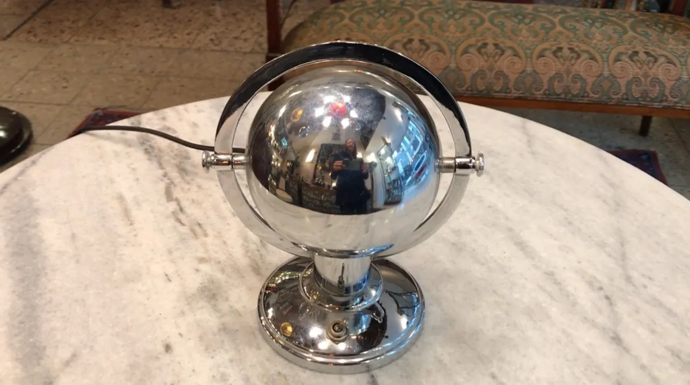 Luminária de mesa antiga com design esférico brilhante em um ambiente clássico.