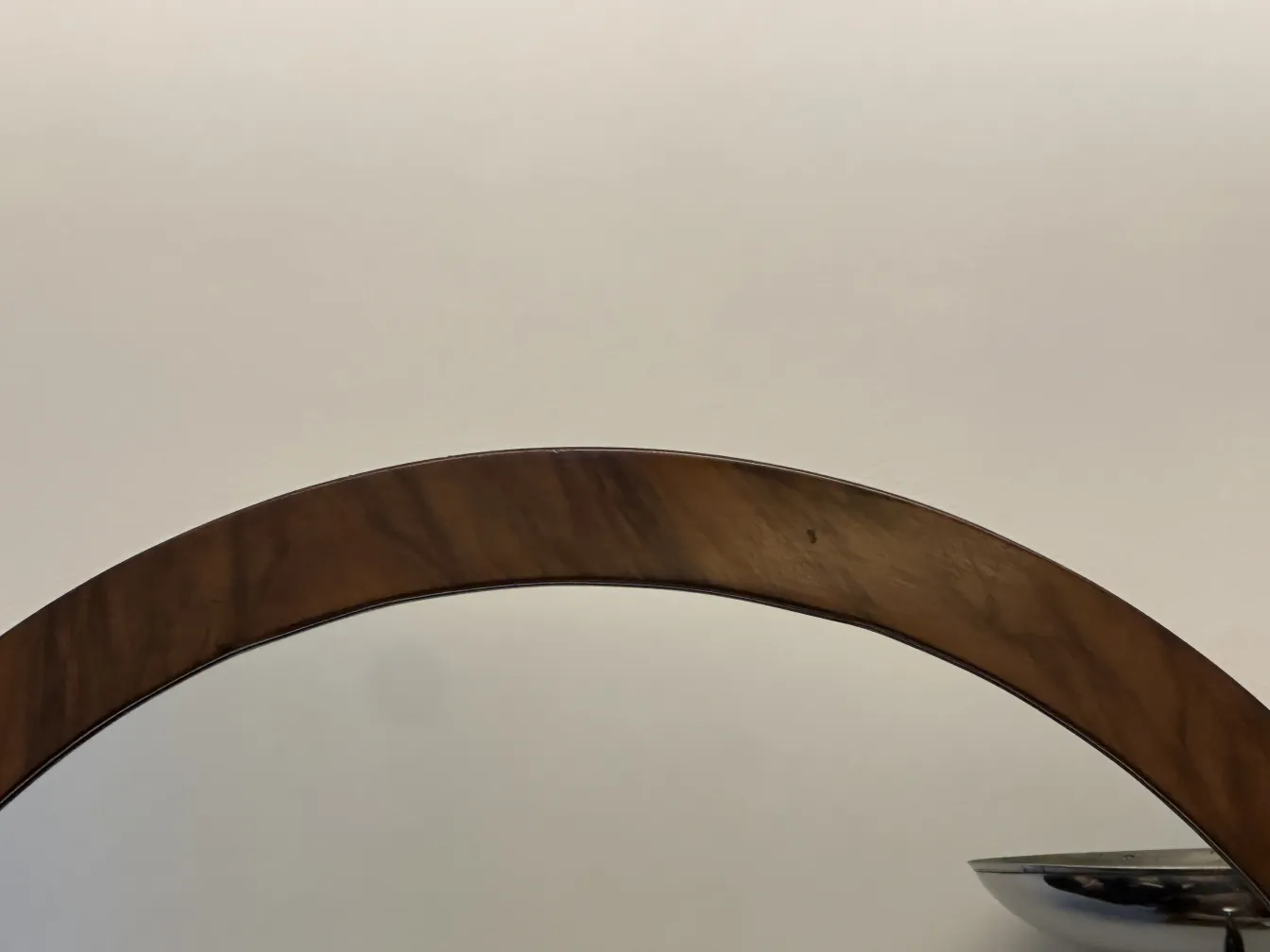 Antique round mirror with decorative border against a neutral background.