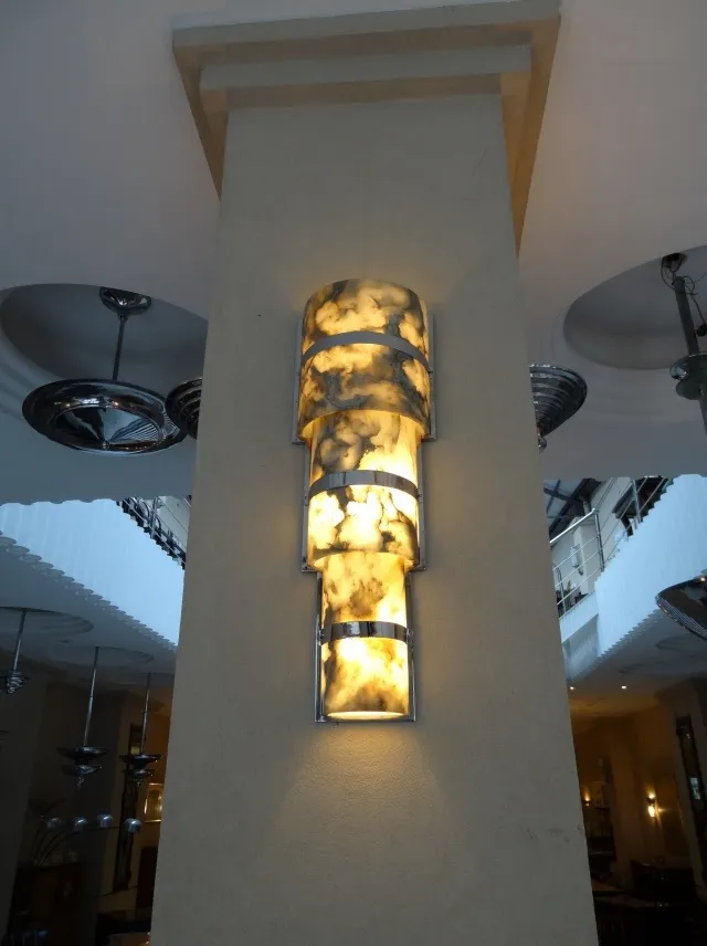 Pair of antique wall sconces on a lit wall, featuring decorative design.