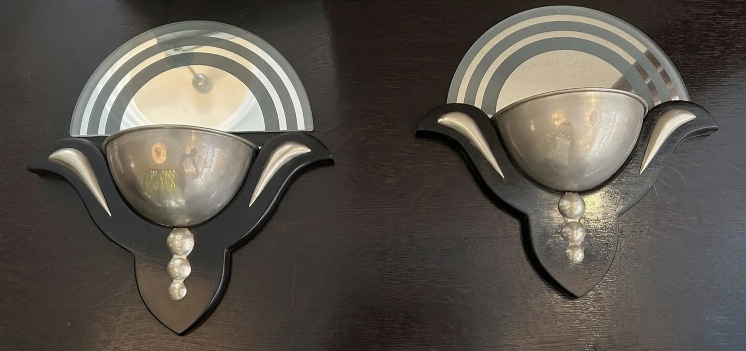 Antique pair of sconces in Art Deco style with elegant finish, decorative panels, and curved shape.