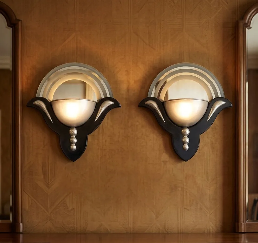 Antique pair of Art Deco sconces with silver details, set against a textured wall background.