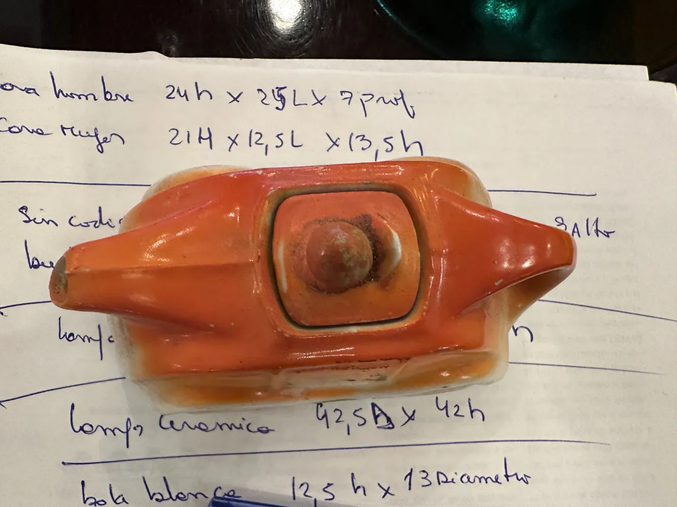 Antike dekorative Keramik in Orange und Weiß, mit markanten Details auf einem beschrifteten Hintergrund.