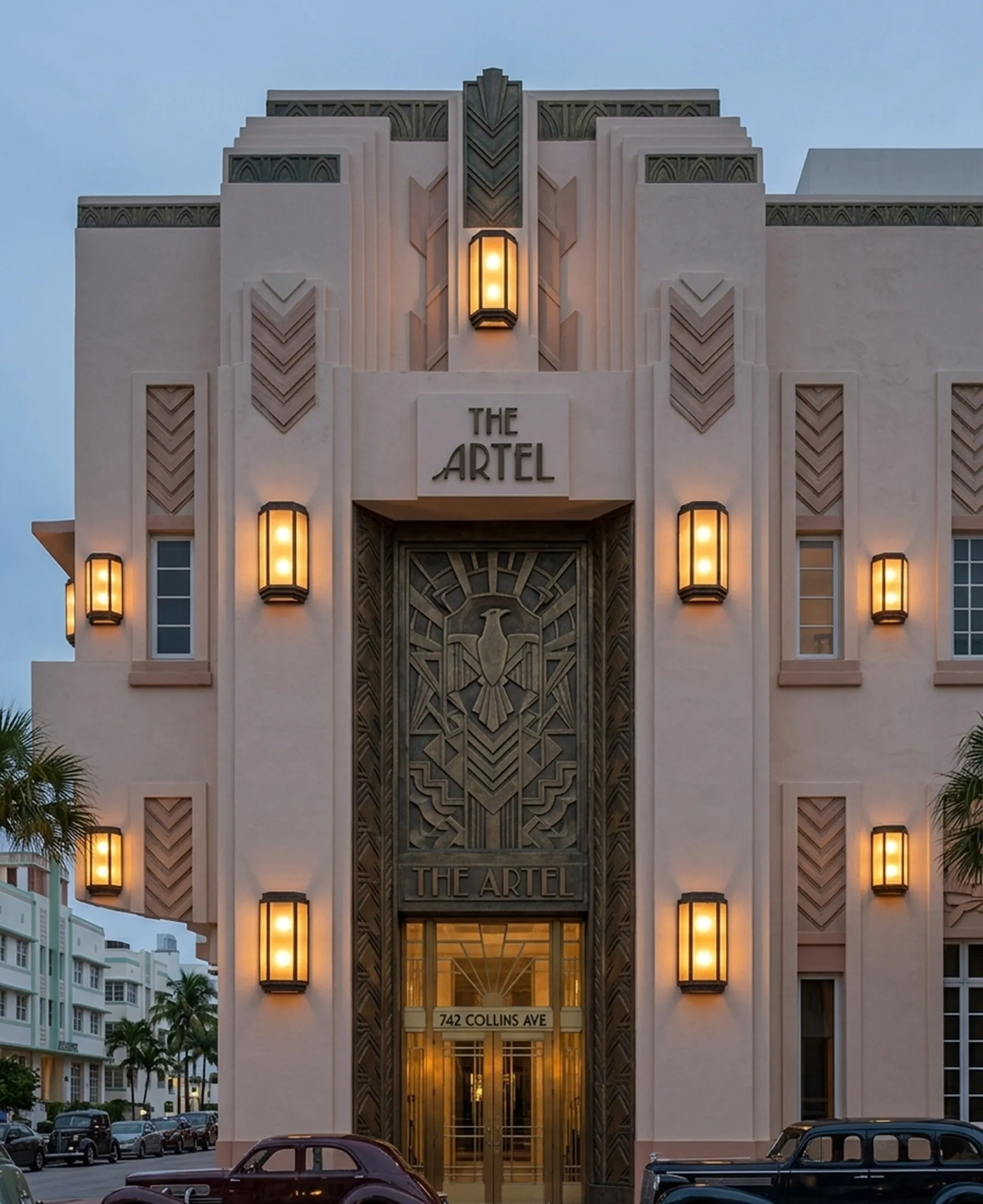 Pair of antique sconces illuminating the entrance of a building, featuring facade details.