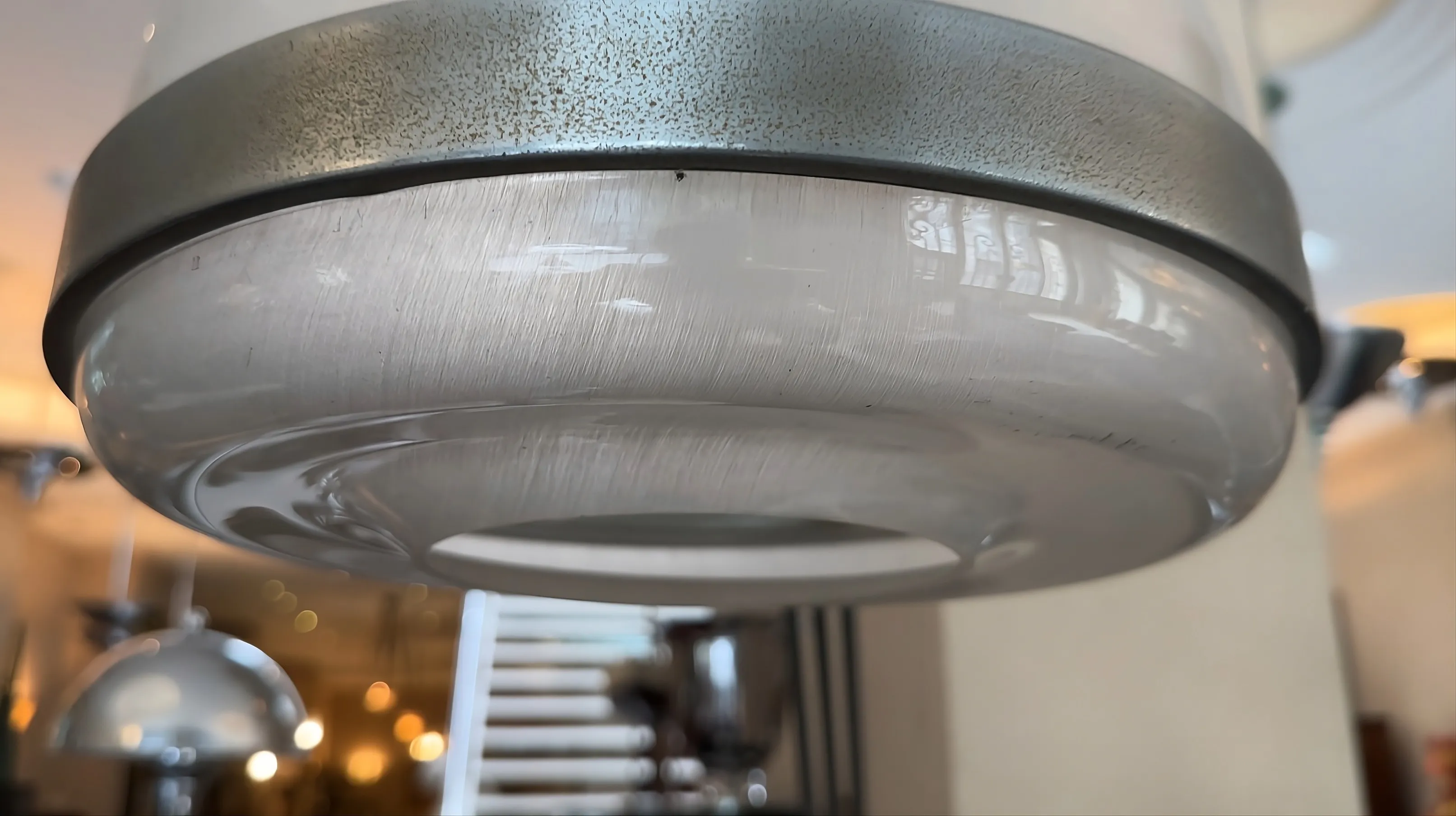 Старая торшер с металлическим основанием и прозрачным абажуром в освещенном окружении.