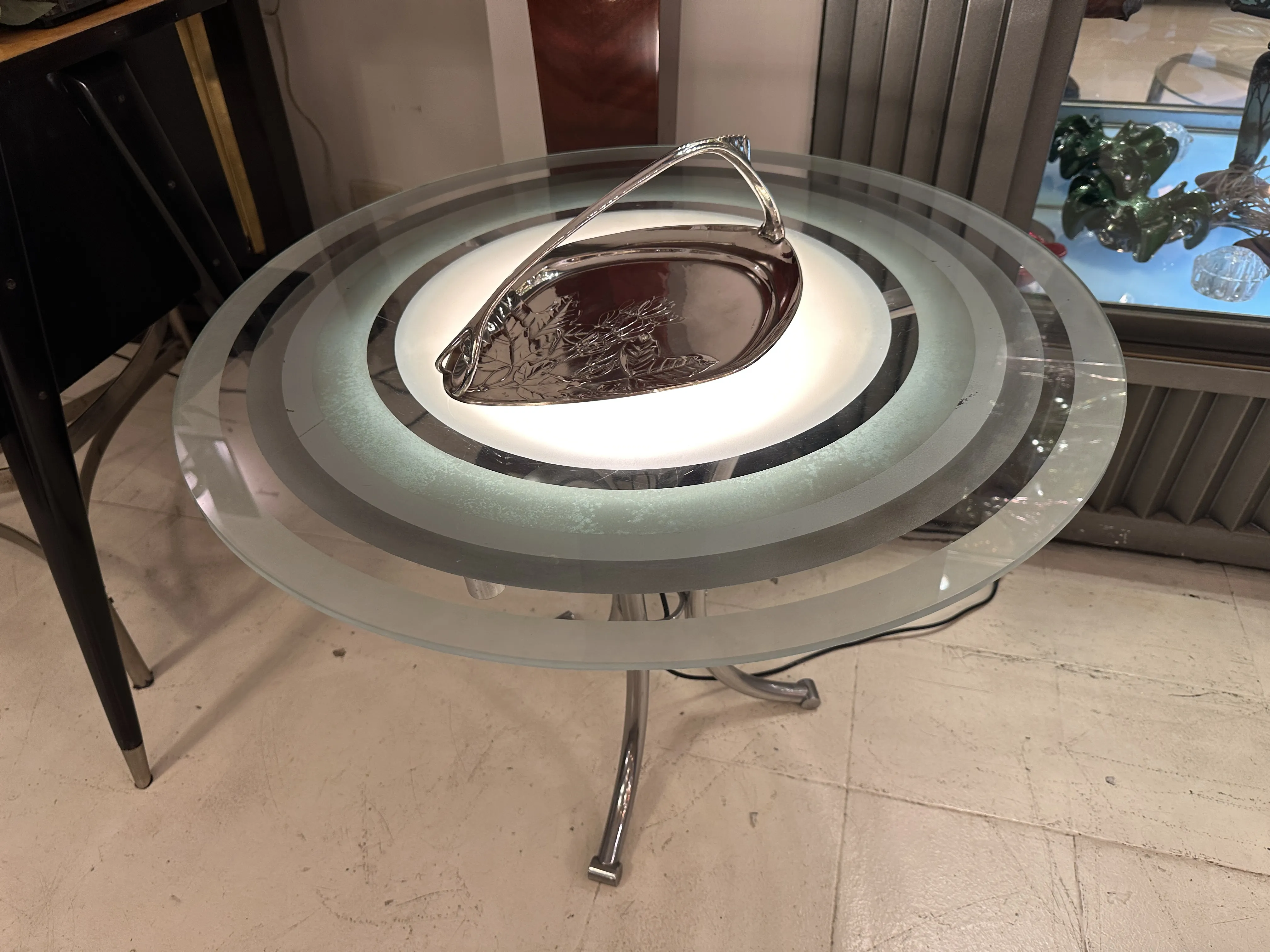 Antique WMF card tray on glass table with decorative background.