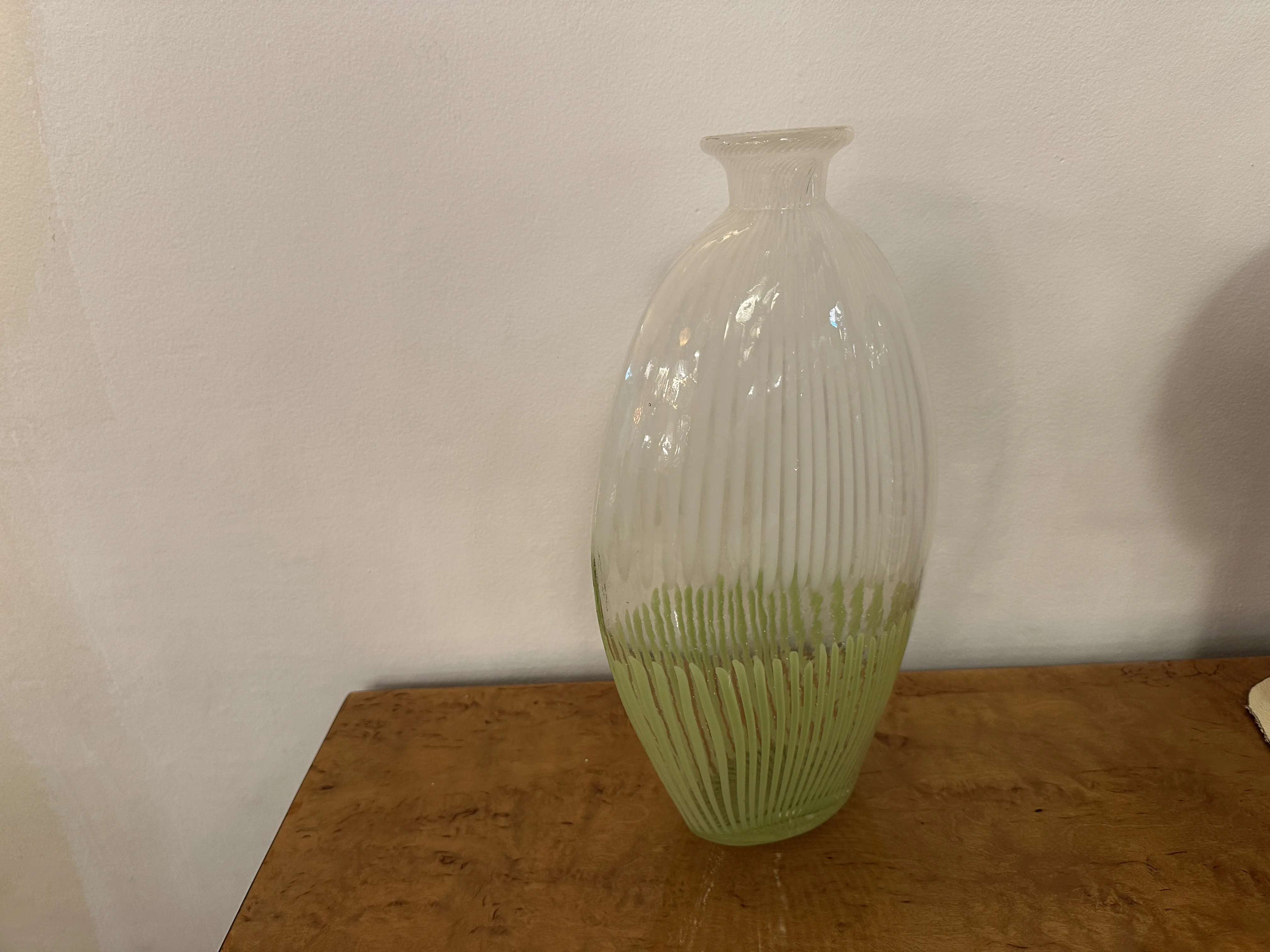 vase di murano antico con forma allungata e dettagli sottili, su un tavolo in legno chiaro