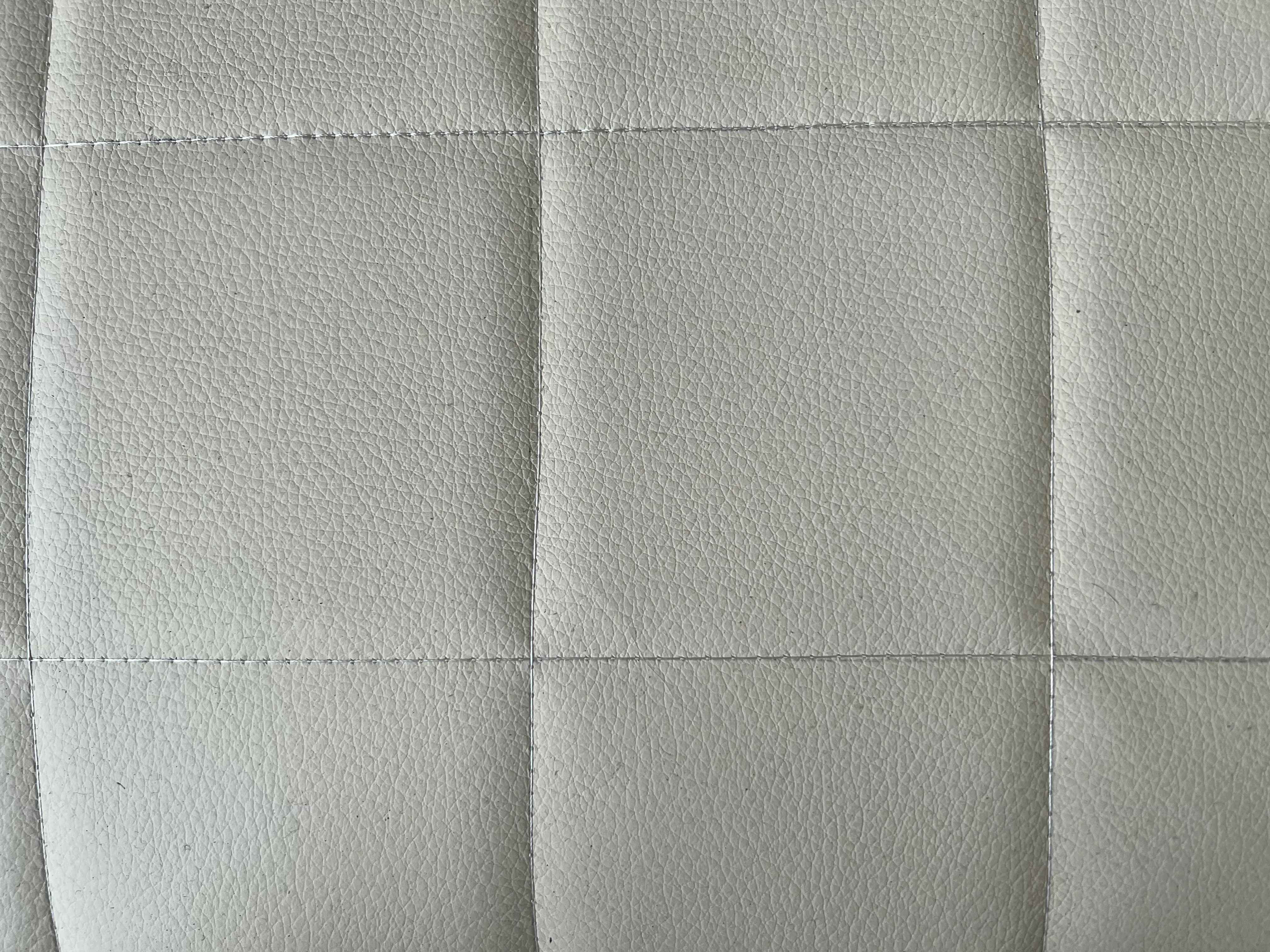 Close-up of 2 vintage armchairs in light color, highlighting texture and design.